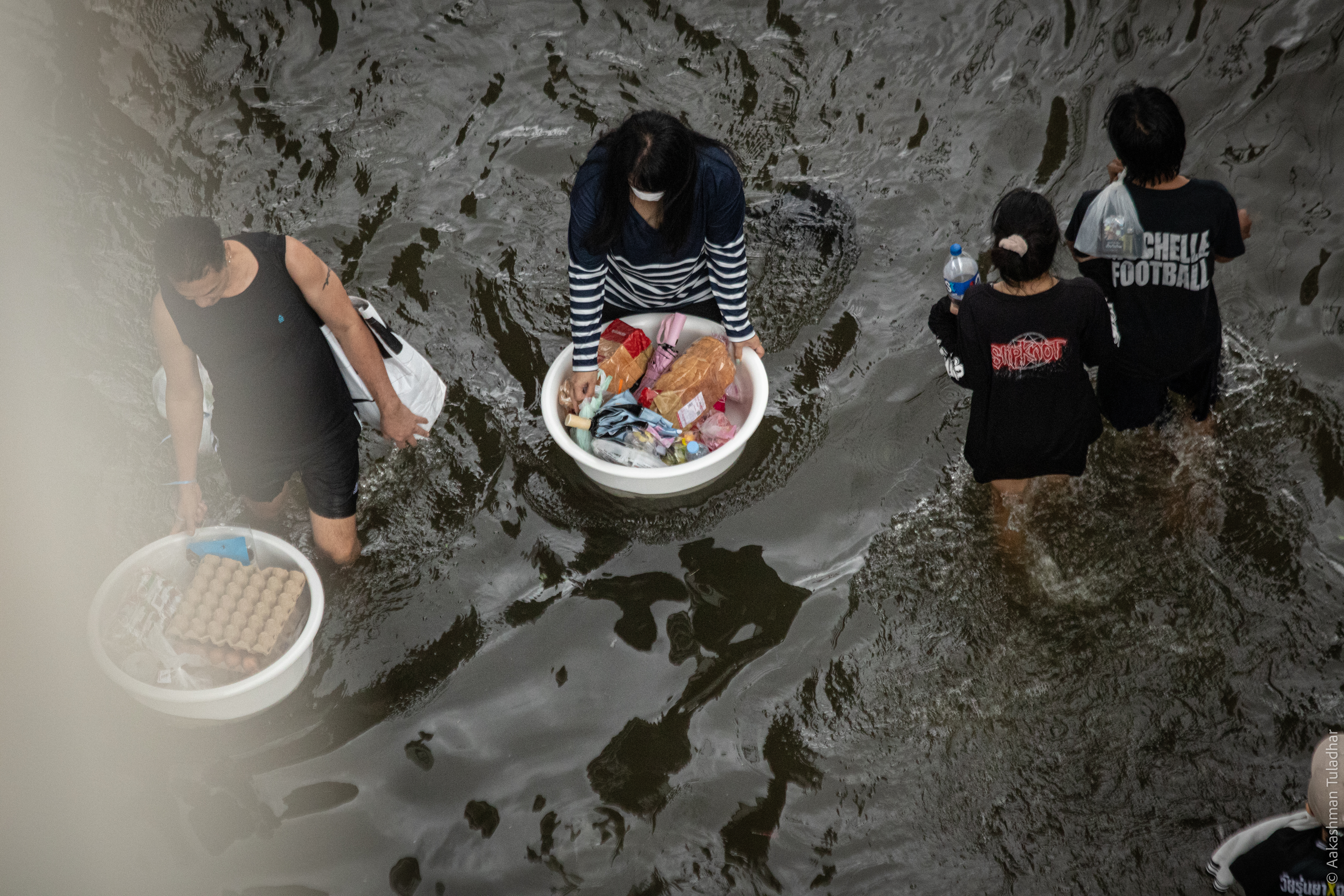 Man with umbrella walking through deep floodwater under an overpass