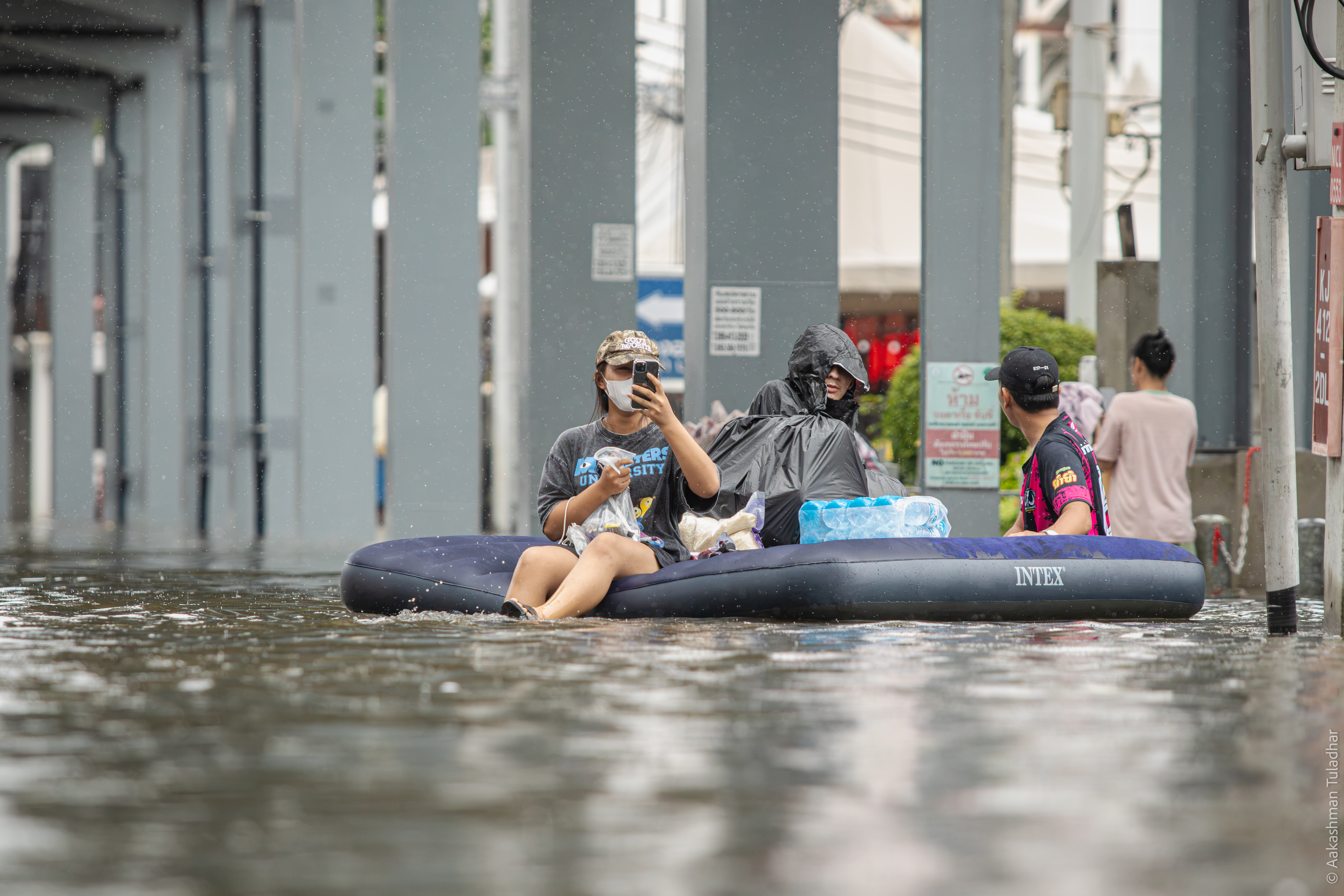 Family on an inflatable mattress navigating Bangkok floods