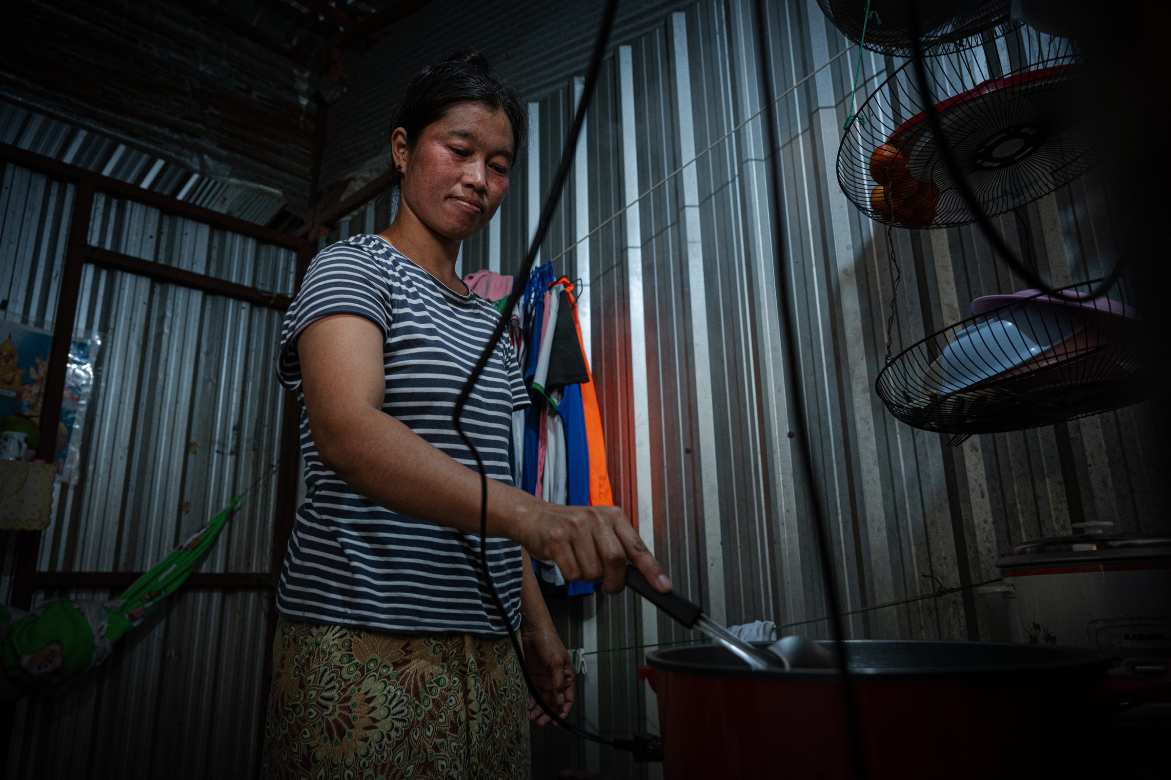 Woman cooking inside a corrugated metal shelter