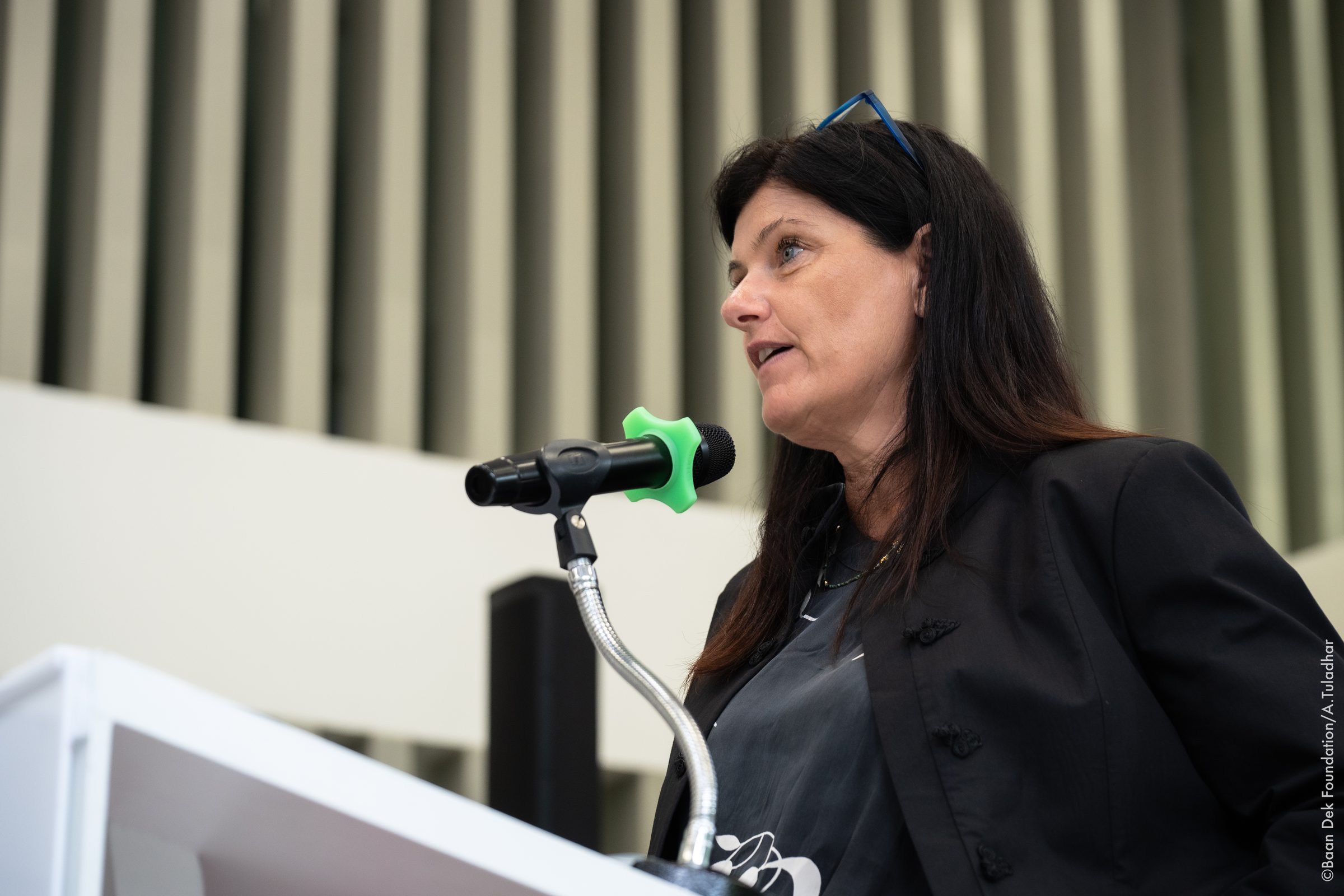 Woman speaking at a podium with a microphone at a Baan Dek Foundation event