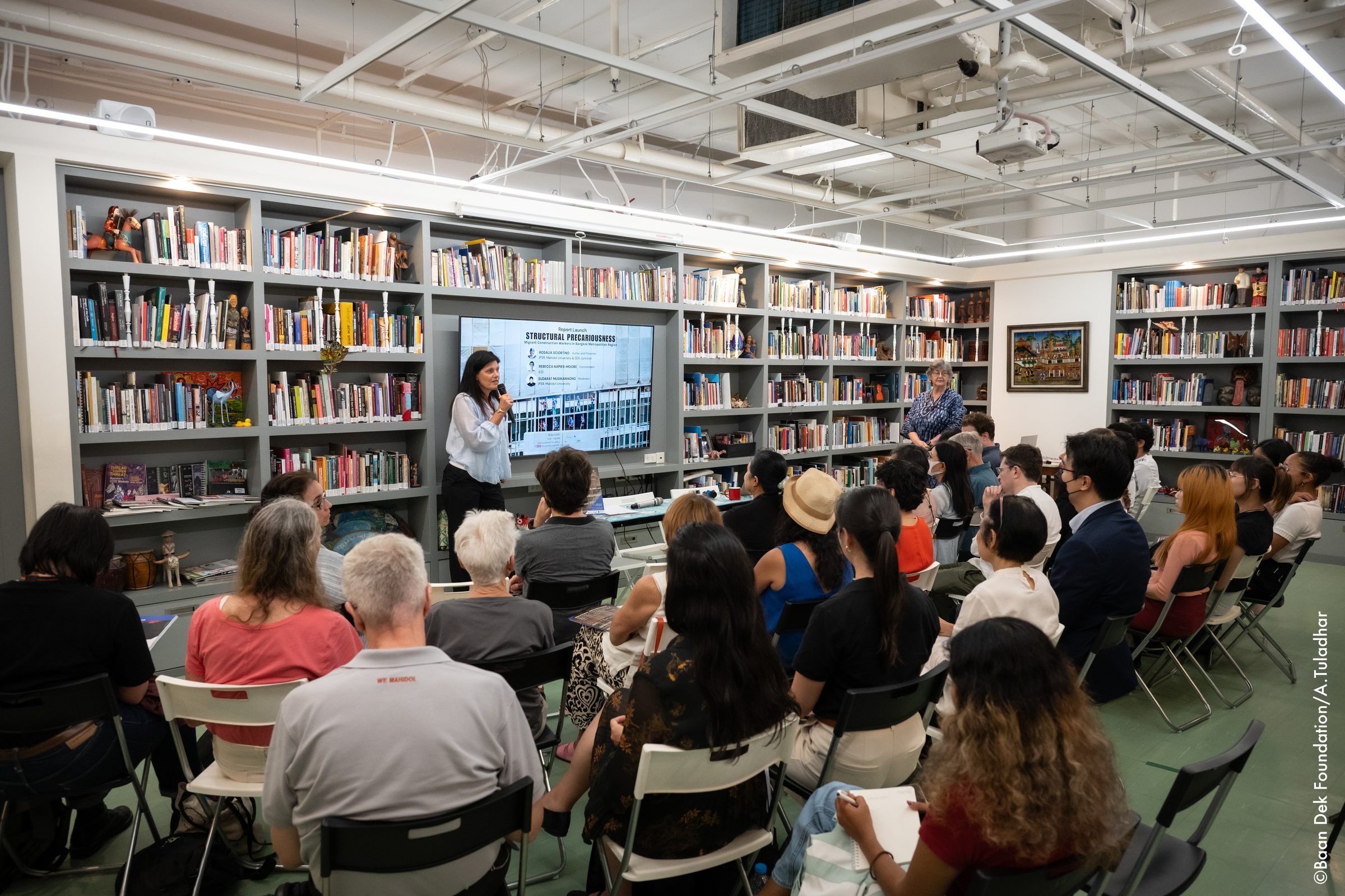 Speaker presenting a report launch to a seated audience in a library