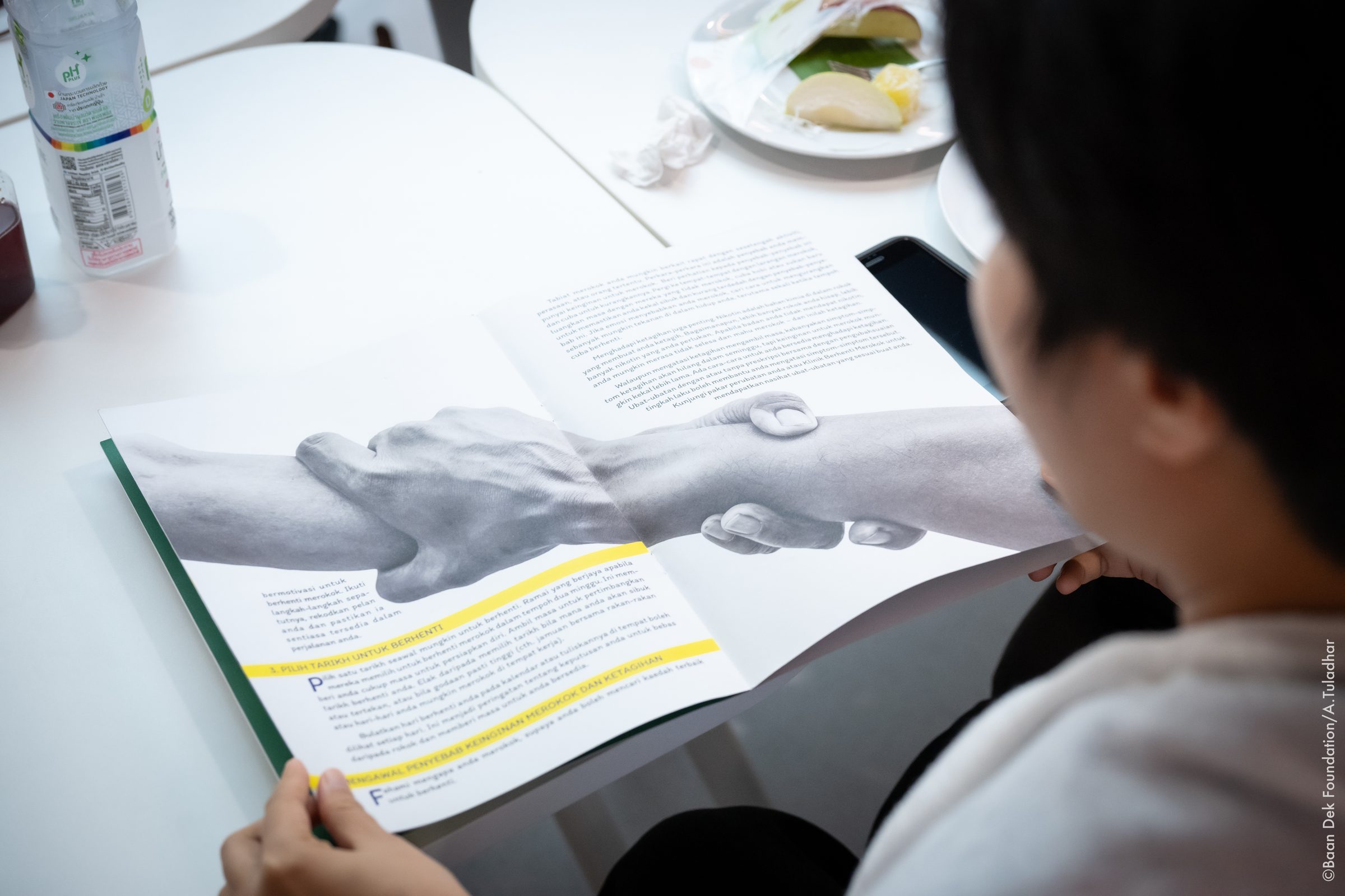 Participant reading a health booklet at a workshop table